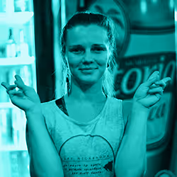 Smiling young woman with hair tied back making an air quotes gesture with both hands.