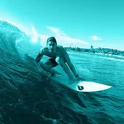Surfer riding a wave close to shore on a white surfboard.