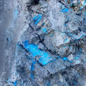 Close-up of rough rock surface with patches of bright blue mineral deposits.