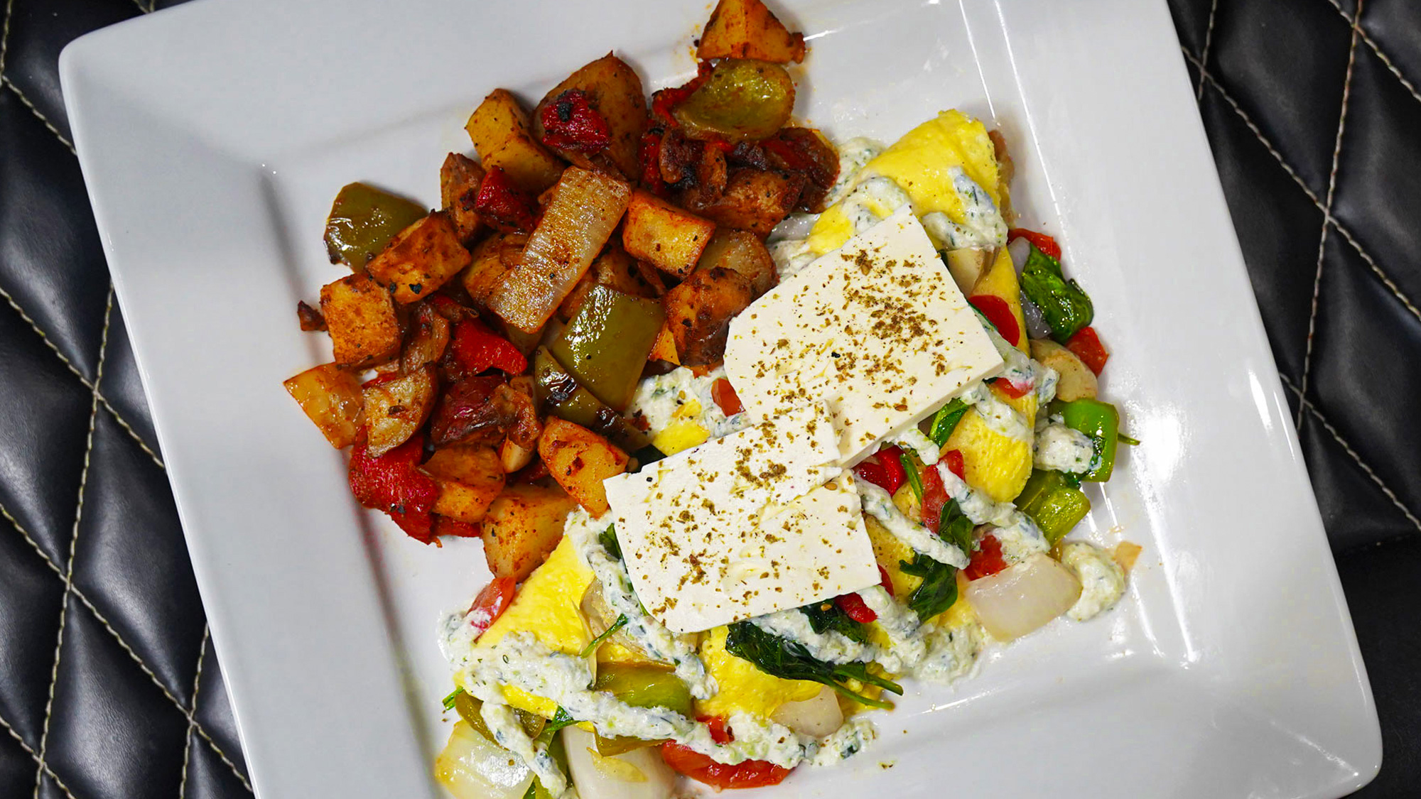 Three egg omelet stuffed with sauteed rustic cut bell peppers, tomatoes, spinach, onions and artichoke hearts finish with feta & tzatziki sauce.