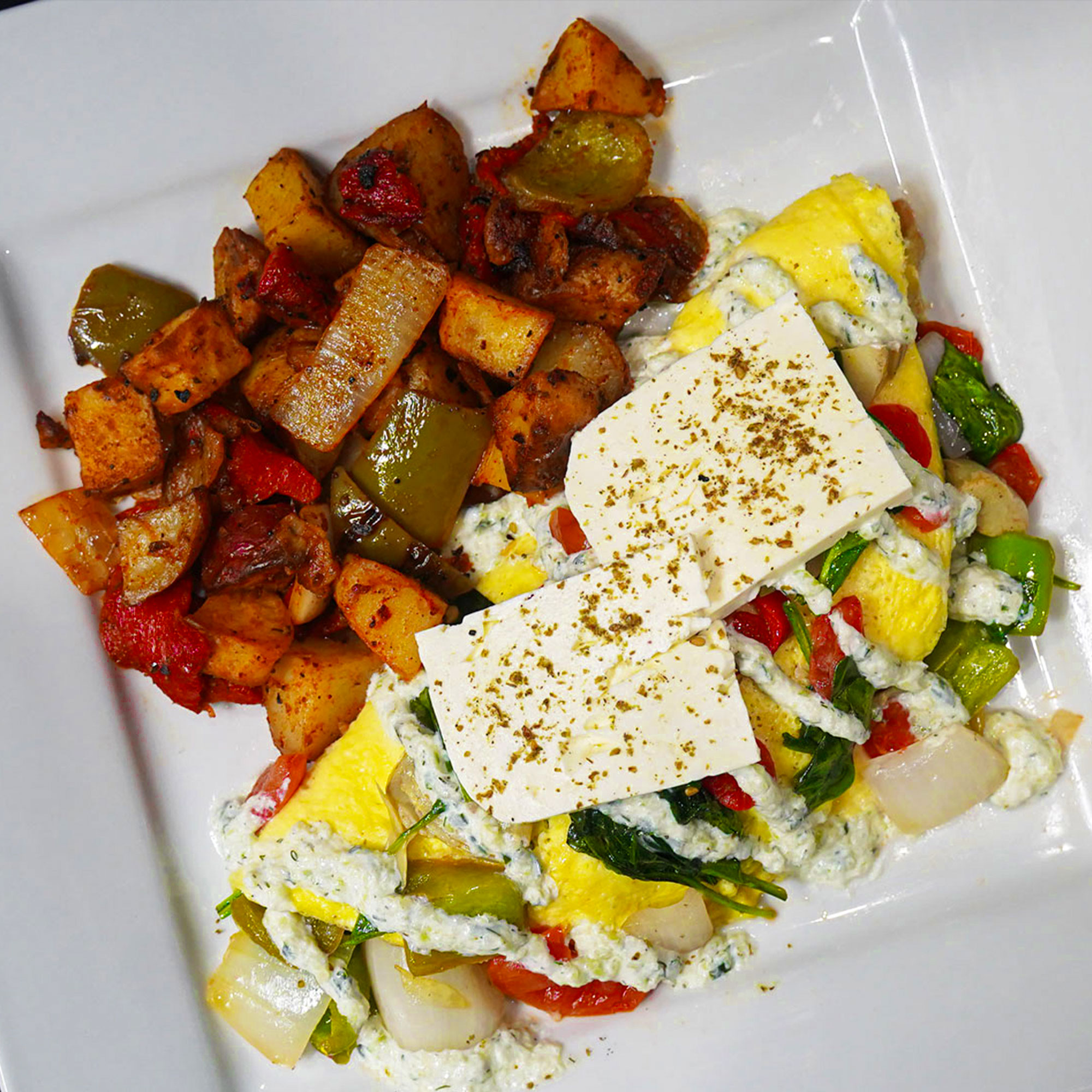 Three egg omelet stuffed with sauteed rustic cut bell peppers, tomatoes, spinach, onions and artichoke hearts finish with feta & tzatziki sauce.