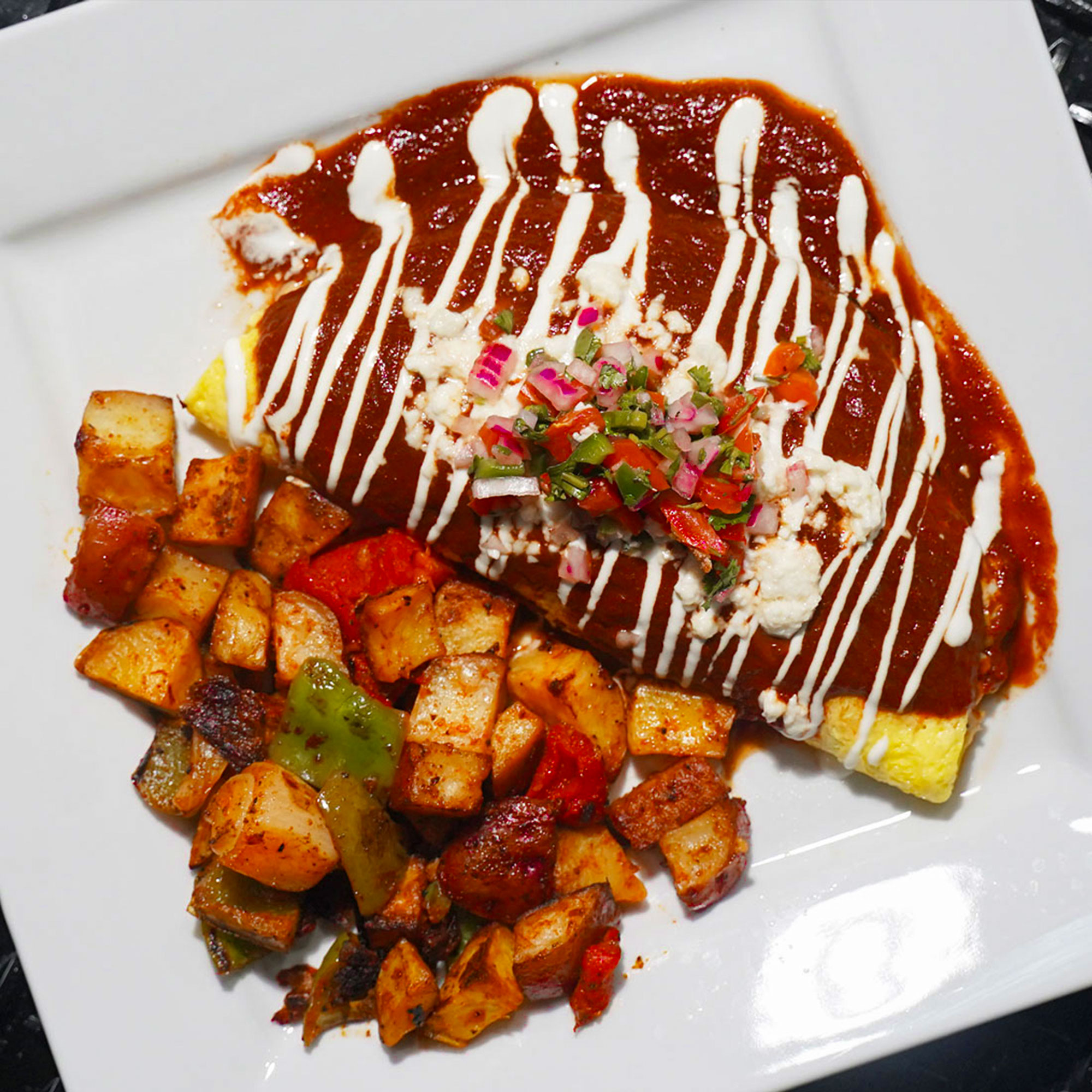 Roasted poblano pepper stuffed with three cheeses & roasted corn, wrapped in a three-egg omelette & topped with red enchilada sauce, crème fraiche, queso fresco & pico de gallo.

