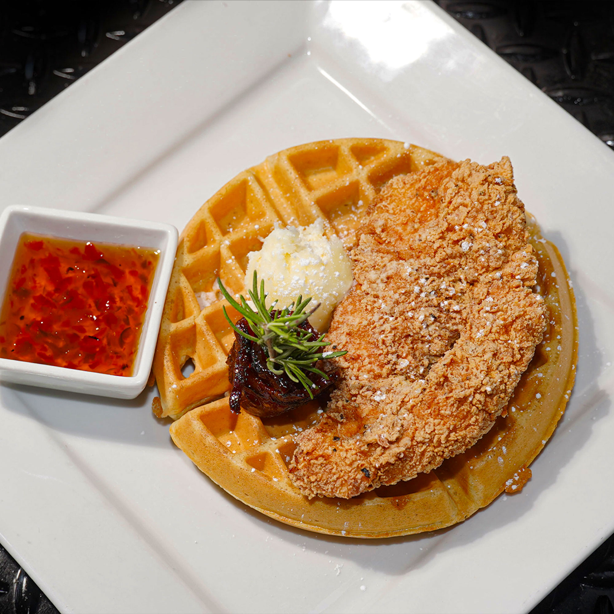 Belgian waffle topped with fried chicken breast, sweet pepper candied bacon, lemon butter, and jalapeño jam.