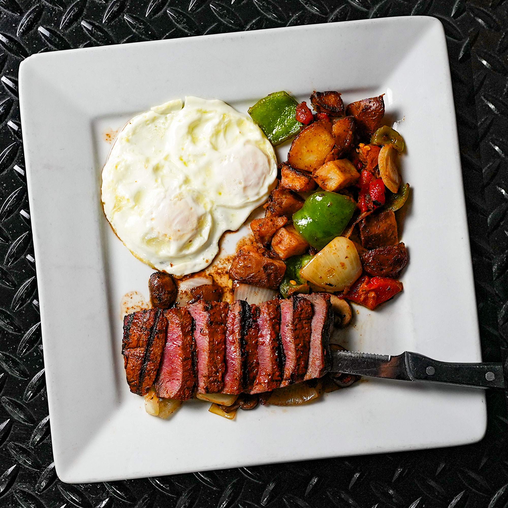 Steak house cut, marinated, flat iron steak set on grilled onions and sliced cremini mushroom with house potatoes and two eggs any style.