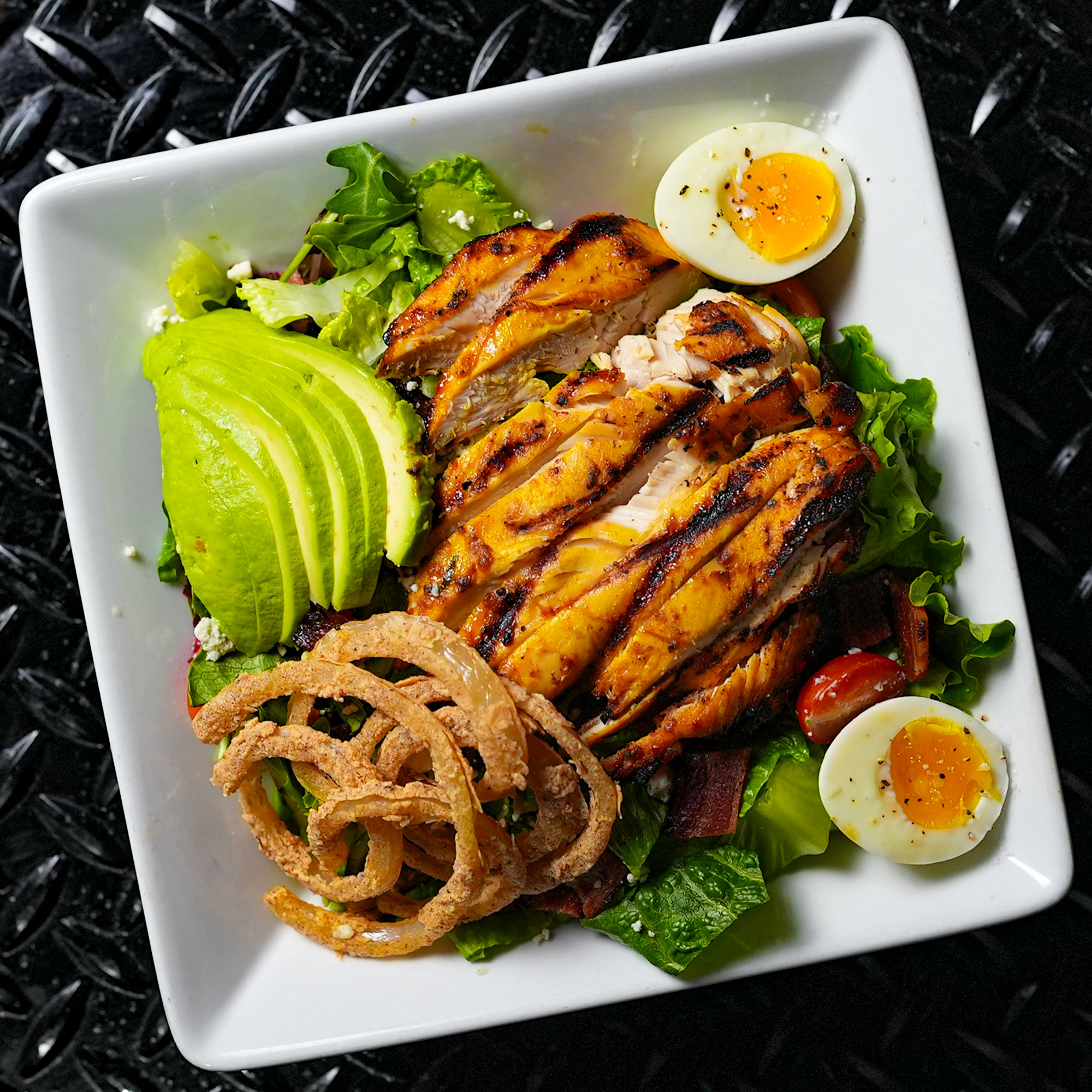 Chopped romaine, arugula and baby mixed greens tossed with creamy blue cheese dressing, blue cheese crumbles, cherry tomatoes, bacon, avocado, crispy onions rings, and jimmy egg