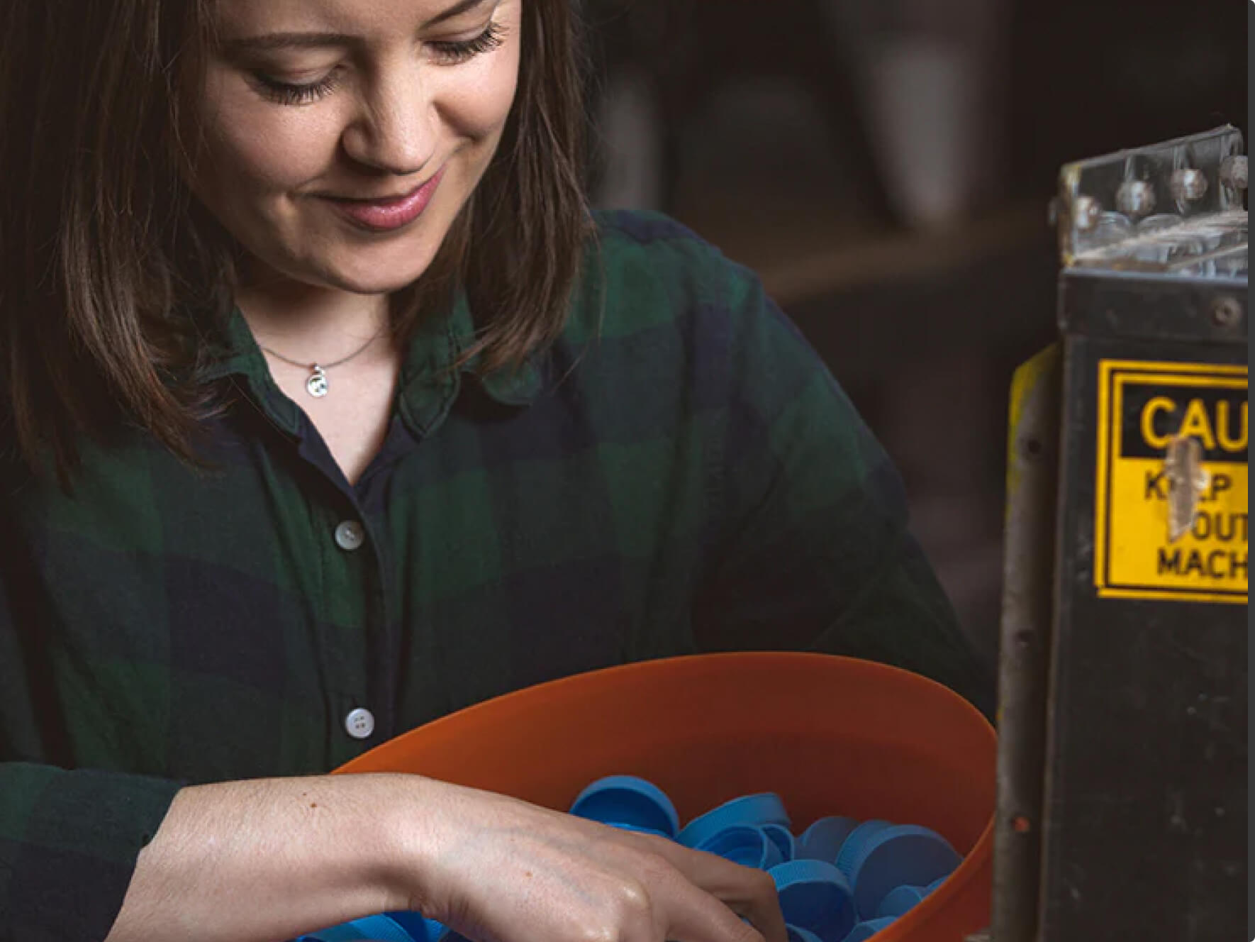 Woman holding bucket of bottle tops ready for recycling.