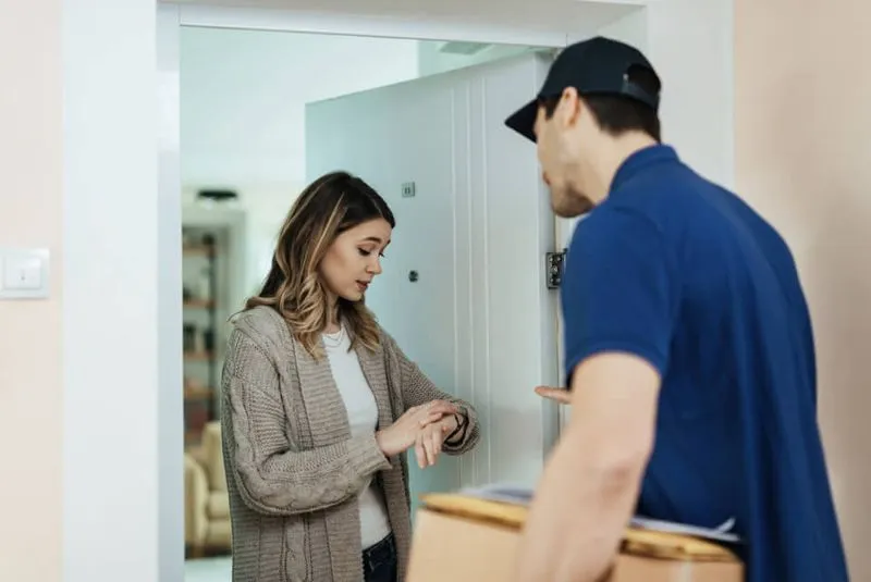 Woman looking at the time while receiving her mail.