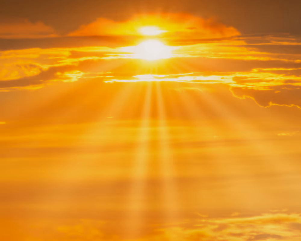 Bright sun shining through golden clouds with sun rays spreading across the sky.