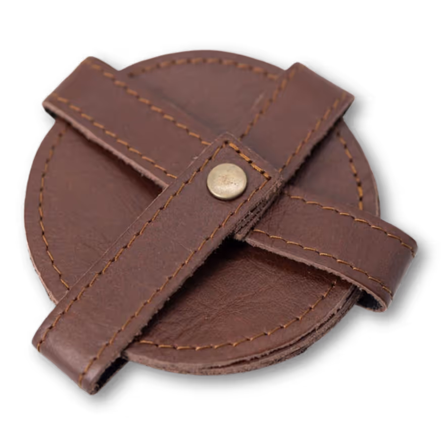 Round brown leather coaster with stitched edges and crossed straps secured by a metal button.