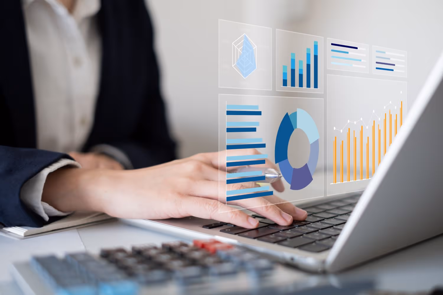 Person tippt auf einem Laptop mit eingeblendeten virtuellen Diagrammen und Grafiken, die Datenanalyse darstellen.