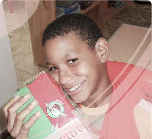 Smiling boy holding a colorful boxed toy close to his face in an indoor setting.