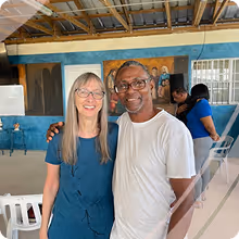 Smiling man, Fransisco, and woman Vivian standing indoors with the man's arm around the woman's shoulder.