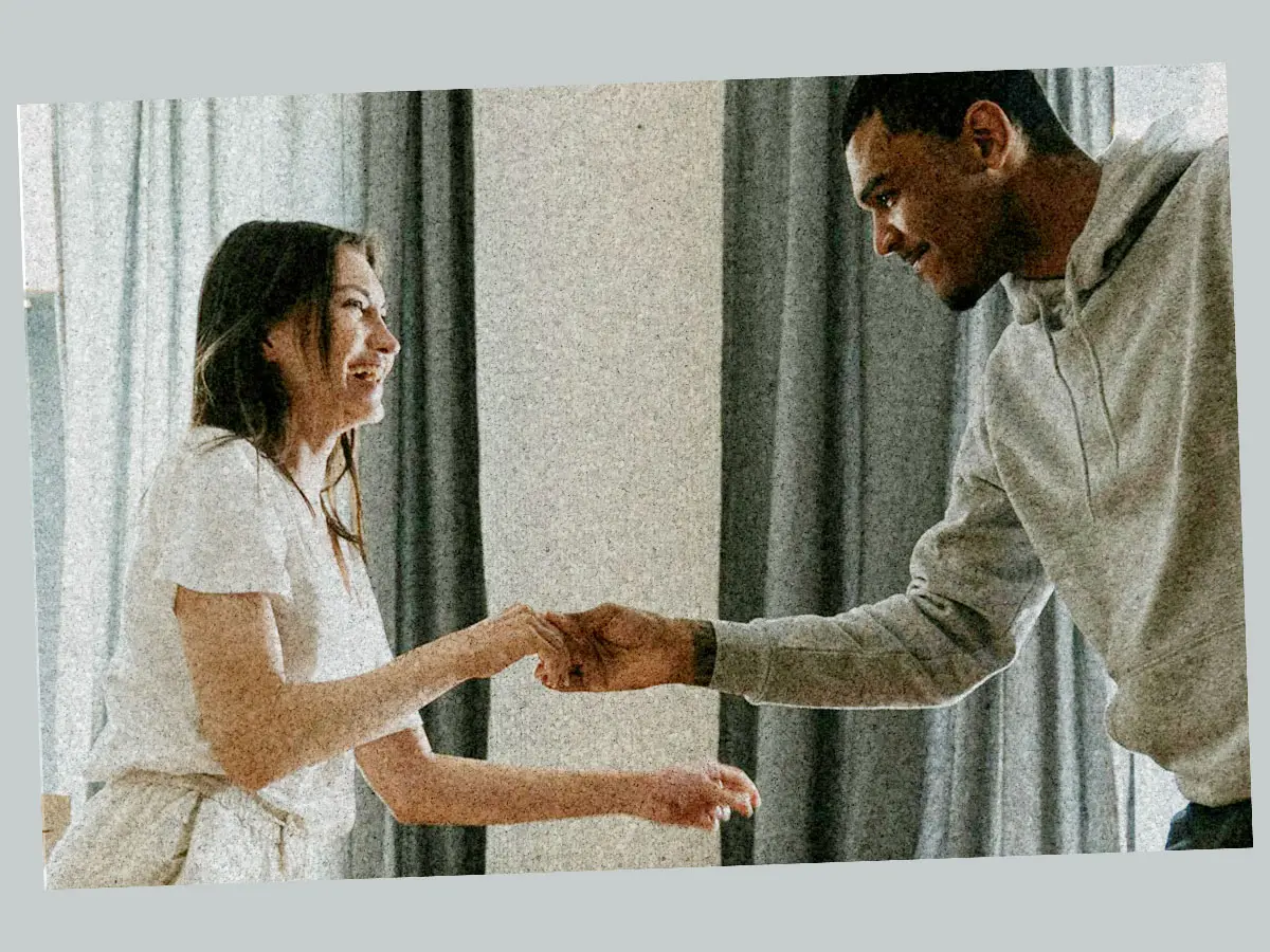 Två personer skrattar och dansar tillsammans i hemmiljö.