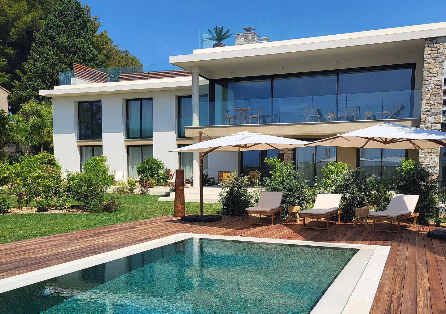 La Villa L'Île Verte éclairée la nuit avec piscine bleue entourée de chaises longues et jardin paysager, La Ciotat