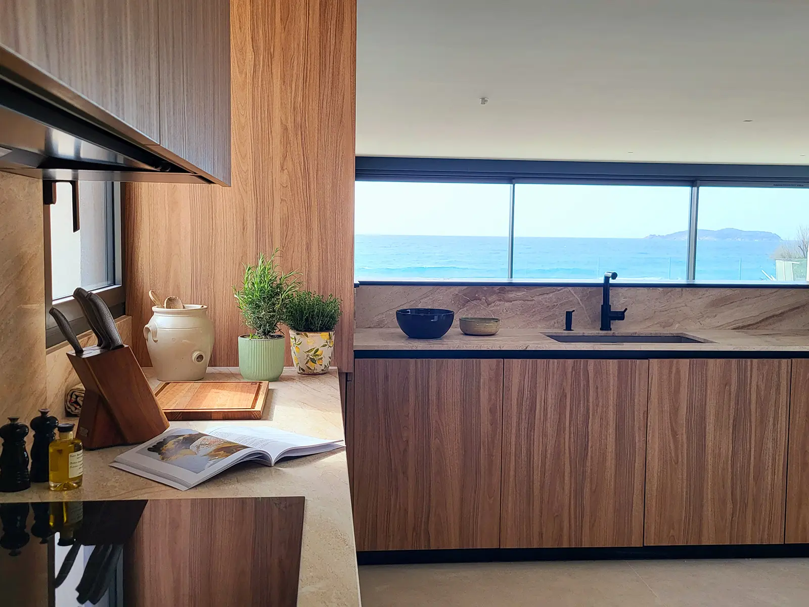 Cuisine moderne de la villa l'île verte avec des placards en bois et une grande fenêtre donnant sur la mer Méditerranée, la Ciotat.