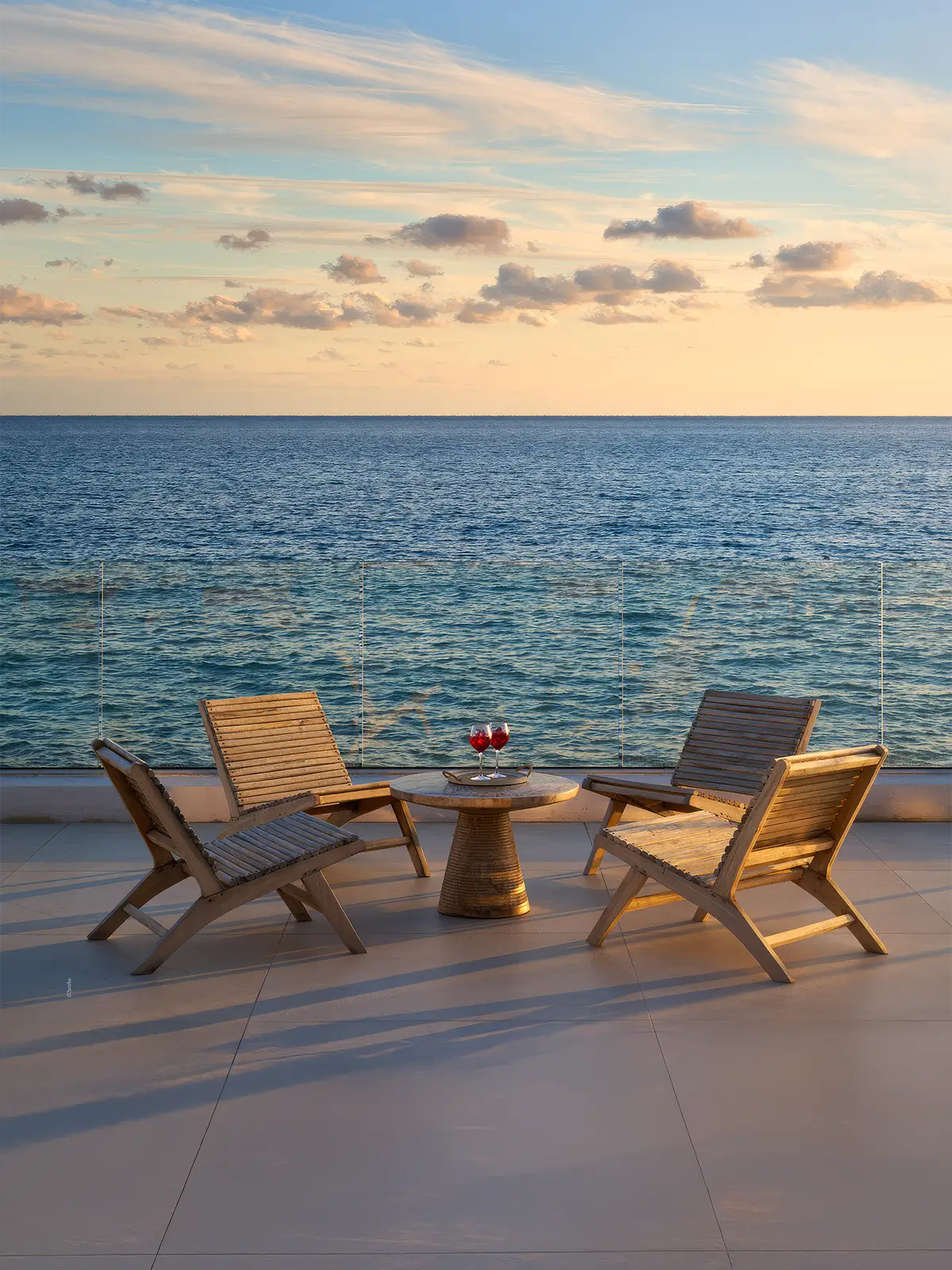 Terrasse avec table et chaises en bois face à la mer au coucher du soleil – vue panoramique depuis La Villa L’Île Verte, villa de luxe à La Ciotat