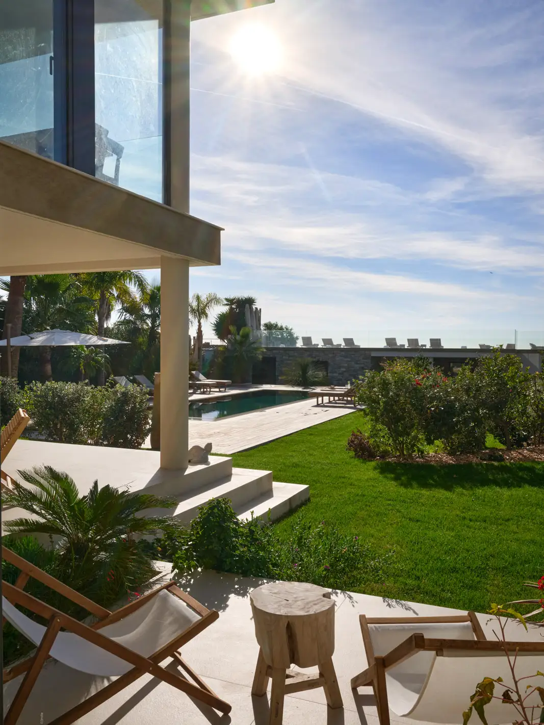 Jardin paysager avec piscine miroir, terrasse en bois et vue mer depuis La Villa L’Île Verte après rénovation à La Ciotat