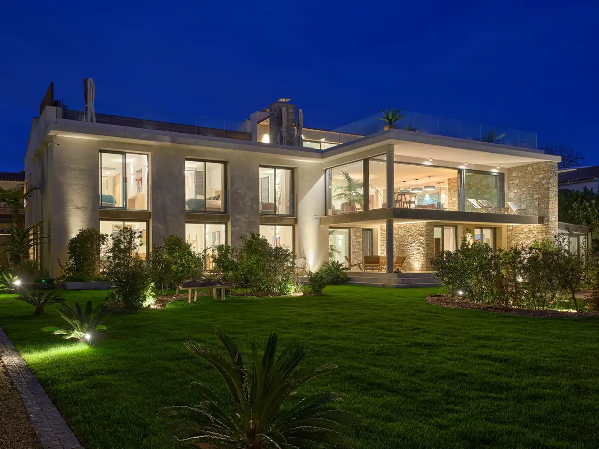Vue nocturne de La Villa L’Île Verte rénovée avec façade contemporaine éclairée et jardin méditerranéen paysager