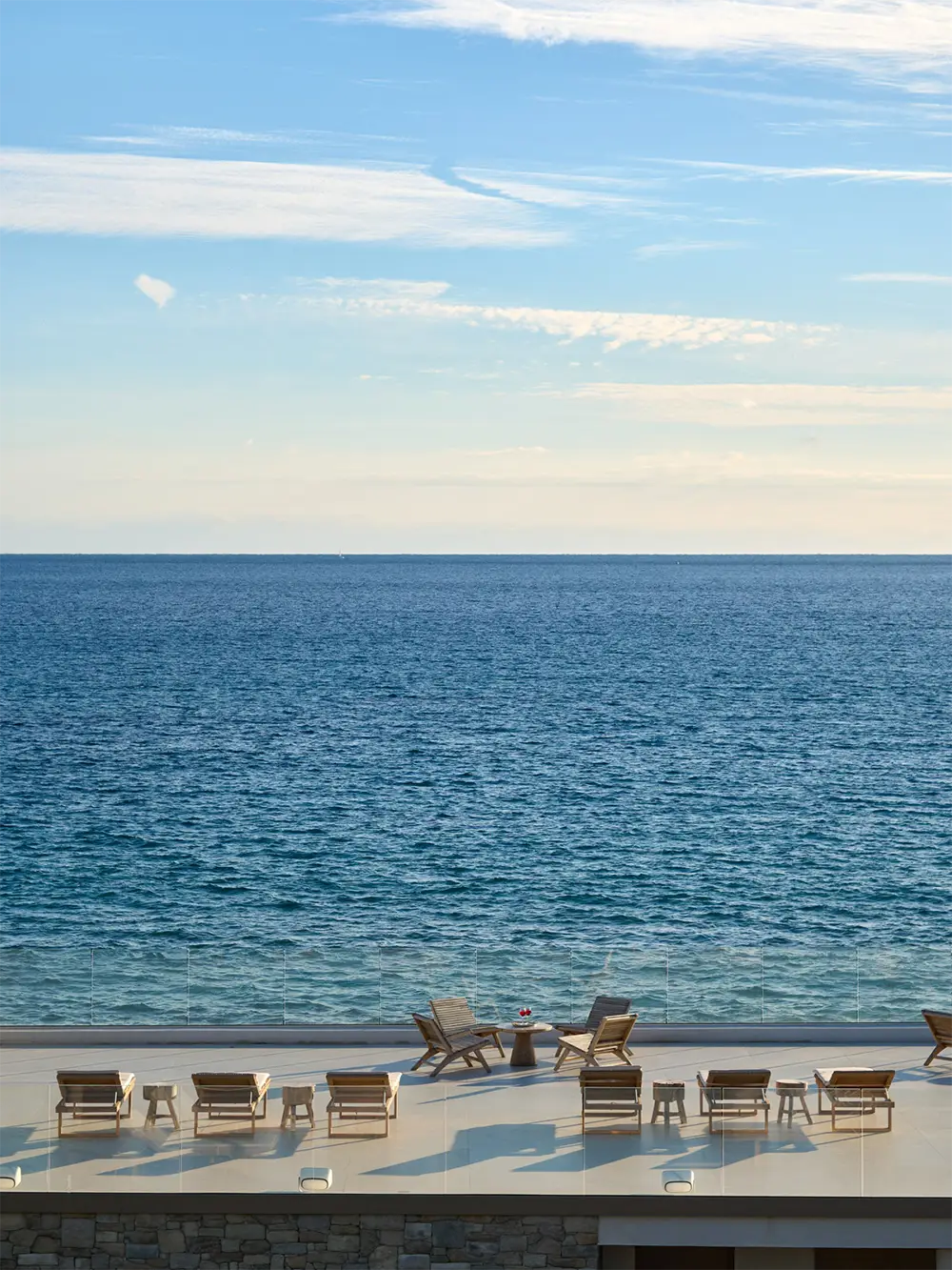 terrasse au-dessus du pavillon de la villa de luxe L’Île Verte avec chaises longues en bois et table d’appoint, offrant une vue panoramique sur la mer Méditerranée à La Ciotat sous un ciel légèrement nuageux