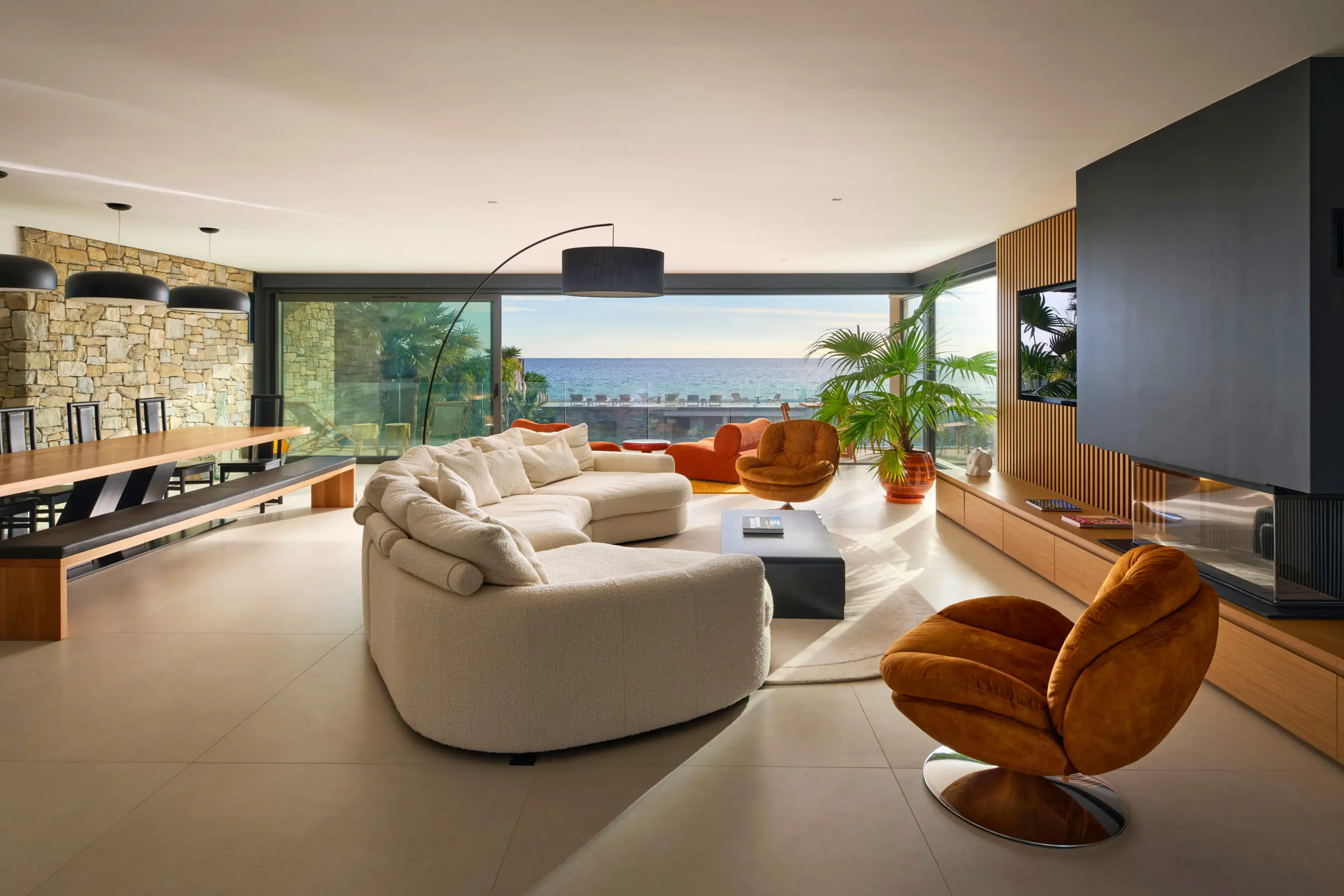 Salon panoramique de La Villa L’Île Verte à La Ciotat avec canapé blanc arrondi, fauteuils design, grandes baies vitrées et vue imprenable sur la Méditerranée.