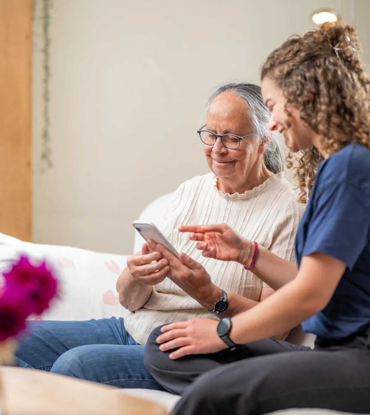 Junge Frau erklärt einer älteren Frau am Handy etwas