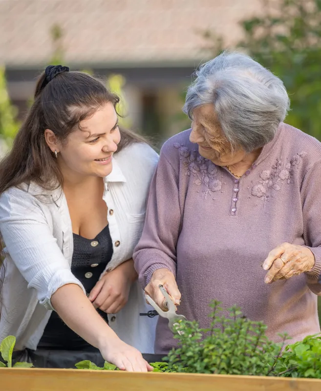 Eine Pflegerin und eine ältere Damen sind bei der Gartenarbeit