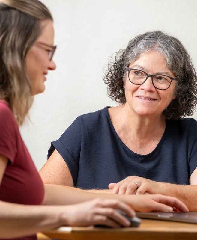 Frau wird von einer Frau am Laptop beraten