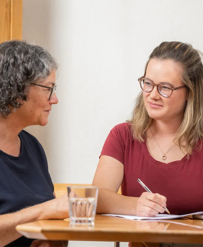Eine Frau beratet eine andere Frau am Tisch