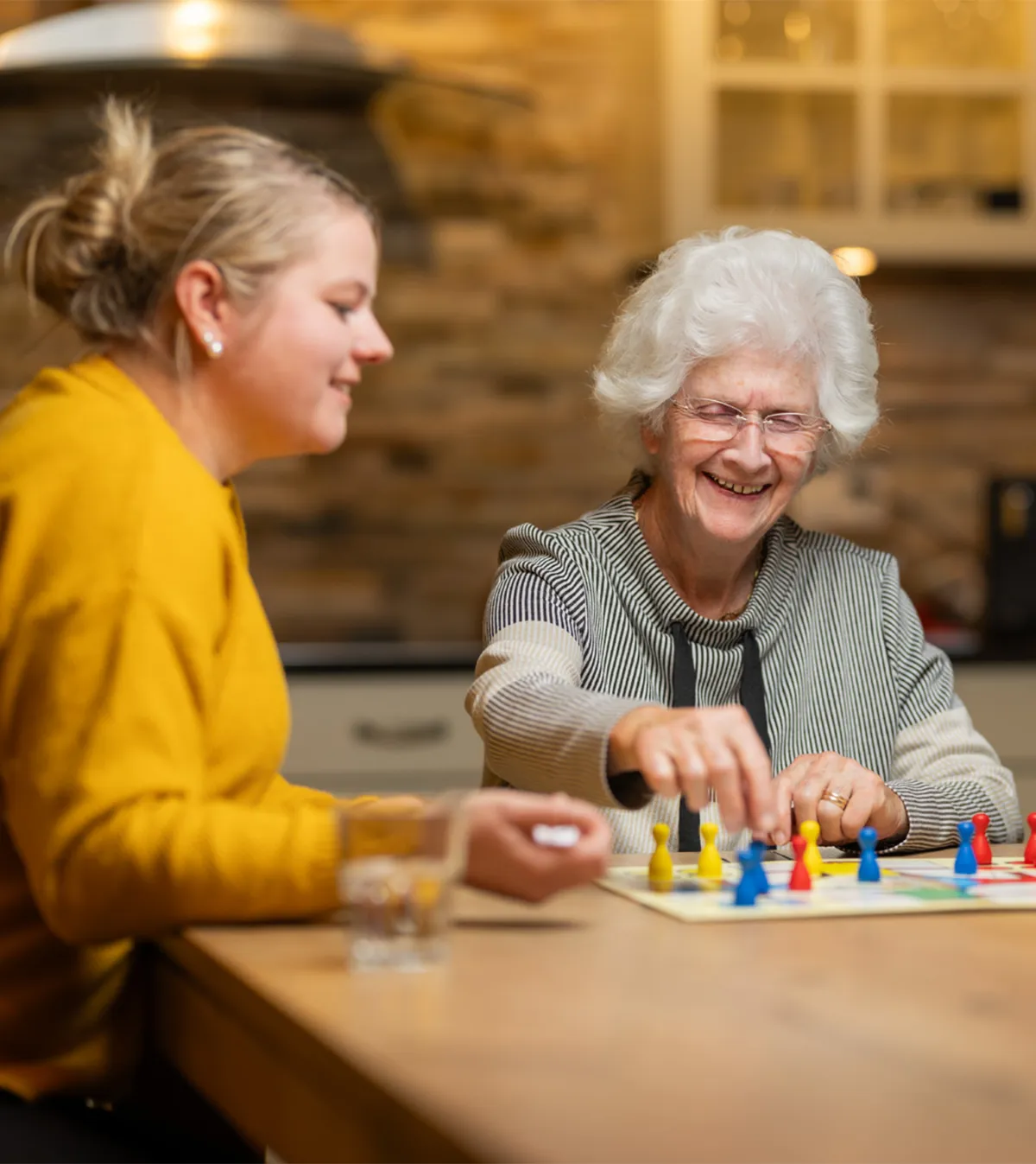 Eine junge und eine ältere Frau sitzen am Tisch und spielen Eile mit Weile