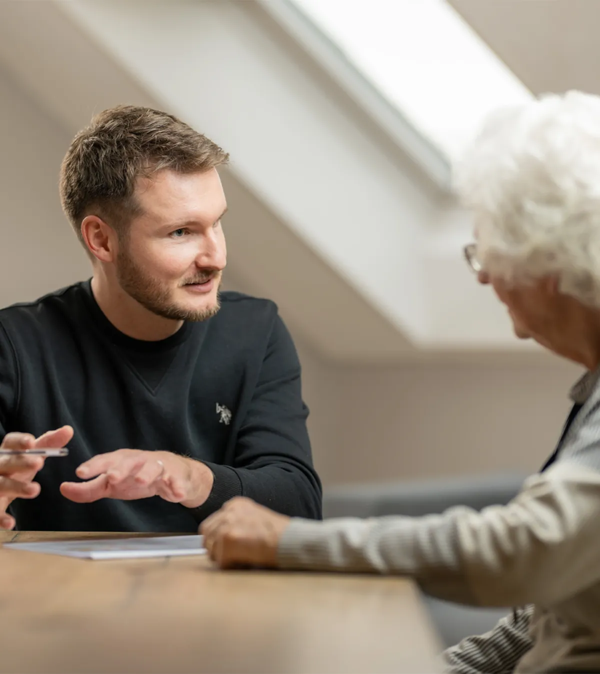 Jonas Gerber, Geschäftsführer der Teba AG beratet eine ältere Frau an einem Tisch