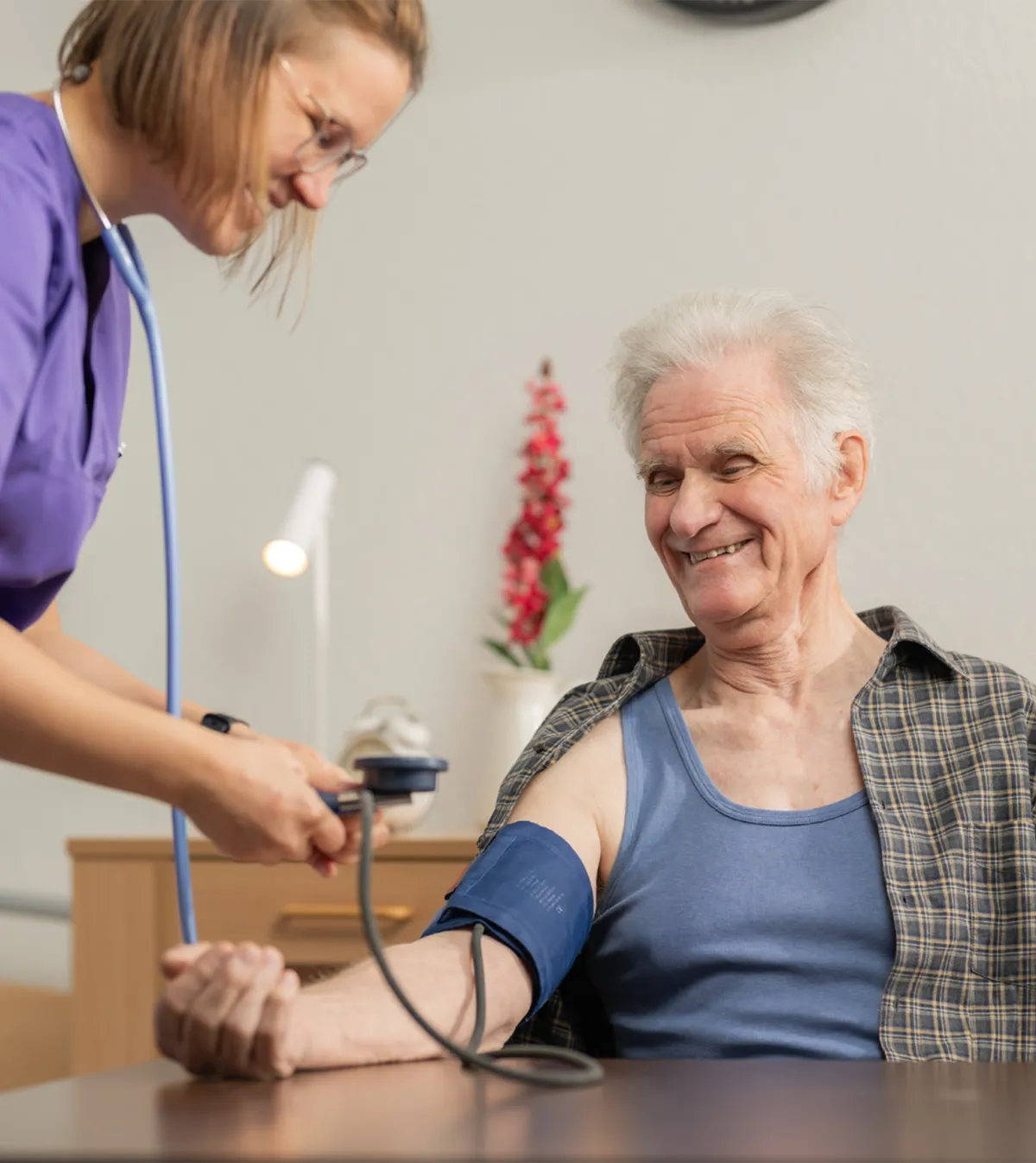 Eine Fachangestellte Gesundheit misst bei einem älteren Mann den Blutdruck