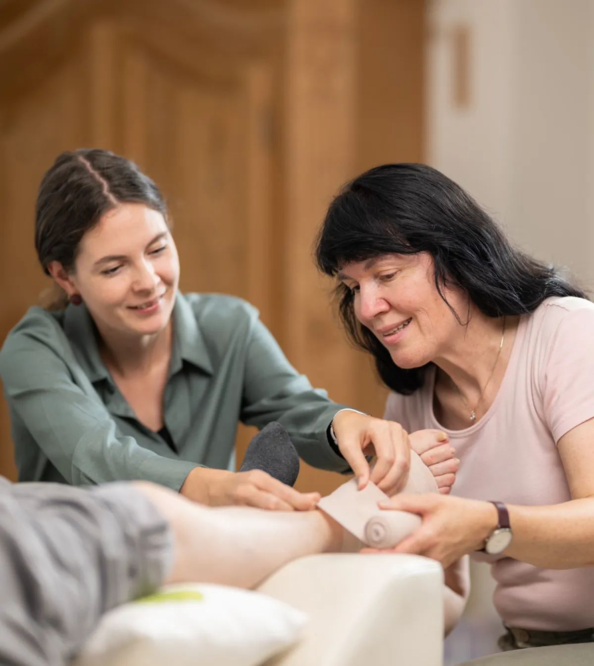 Eine Fachfrau Gesundheit zeigt einer anderen Frau, wie man einen Kompressionsverband anlegt