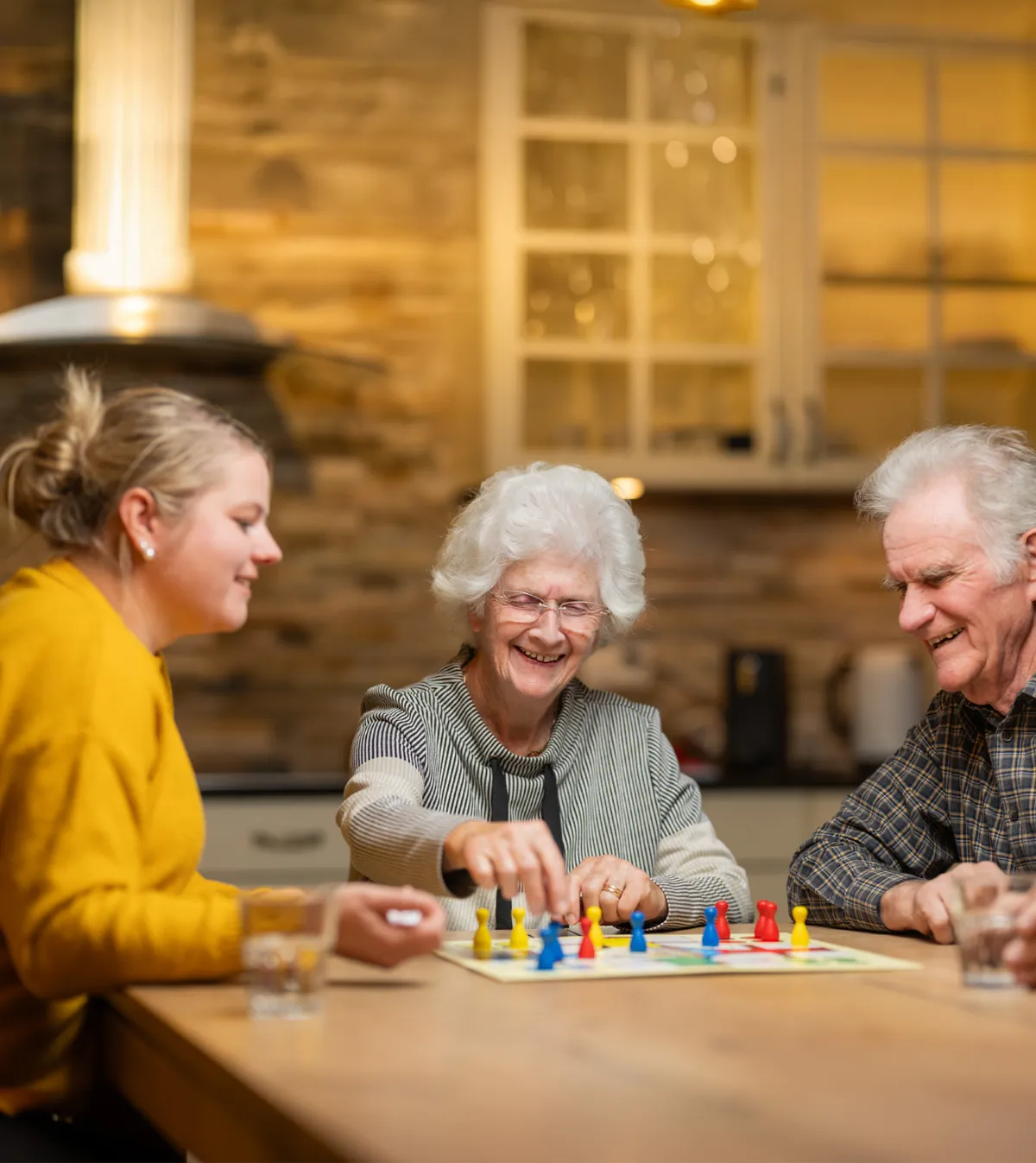 3 Personen spielen Eile mit Weile an einem Küchentisch in gemütlicher Atmosphäre