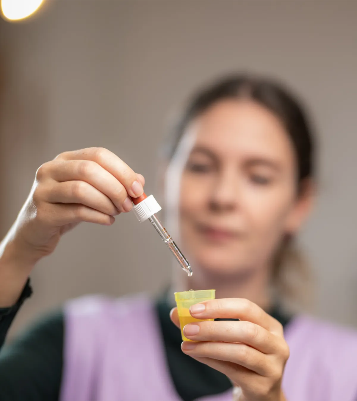 Eine Frau zählt Medikamenten-Tropfen in ein Behälter ab