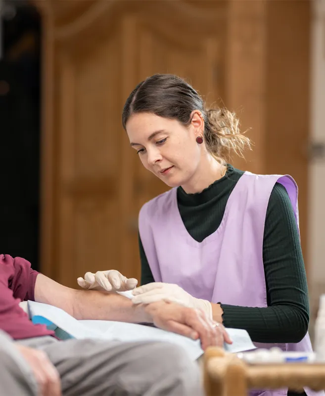 Frau verbindet den Arm eines älteren Menschen.