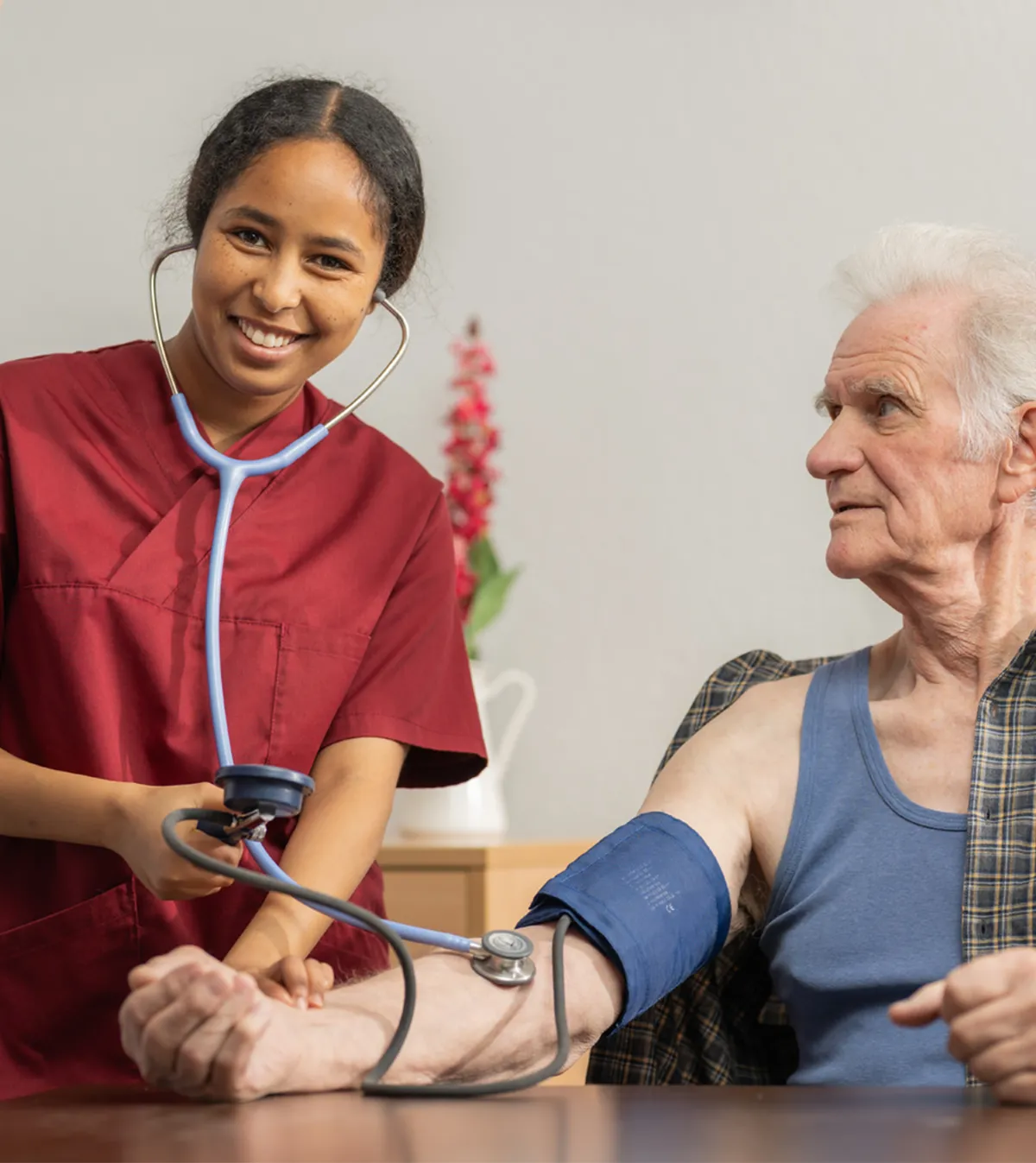 Eine Lernende der Ausbildung FaGe misst den Blutdruck eines älteren Mannes