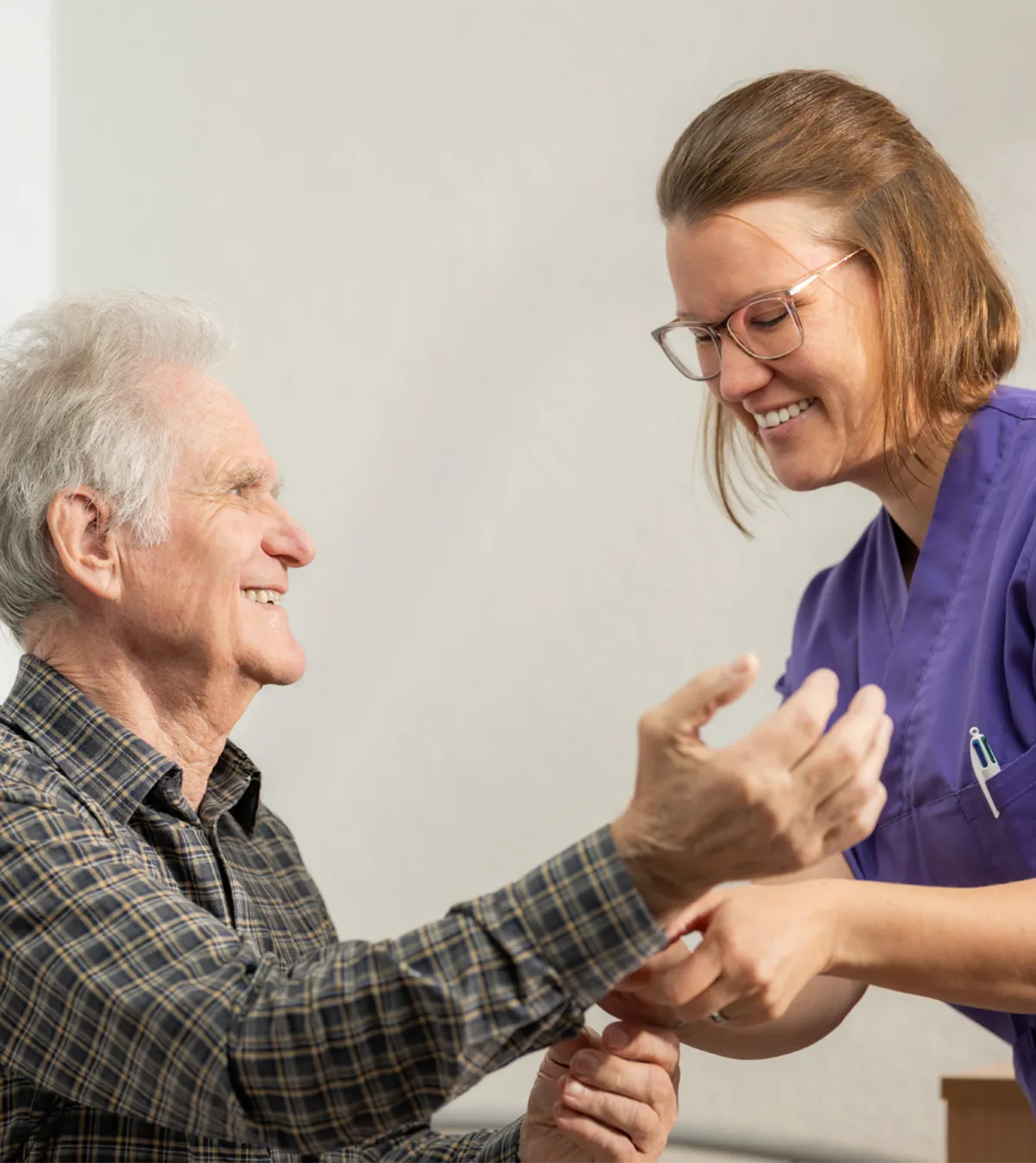 Eine Pflegefachfrau hilft einem älteren Mann bei den Knöpfen seines Hemds