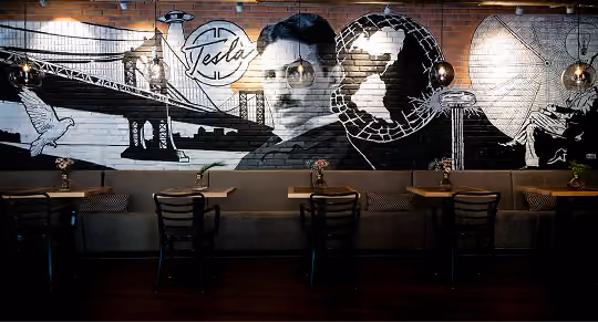 Wandbild von Nikola Tesla über den Sitzplätzen im Tesla Coffee & Concept