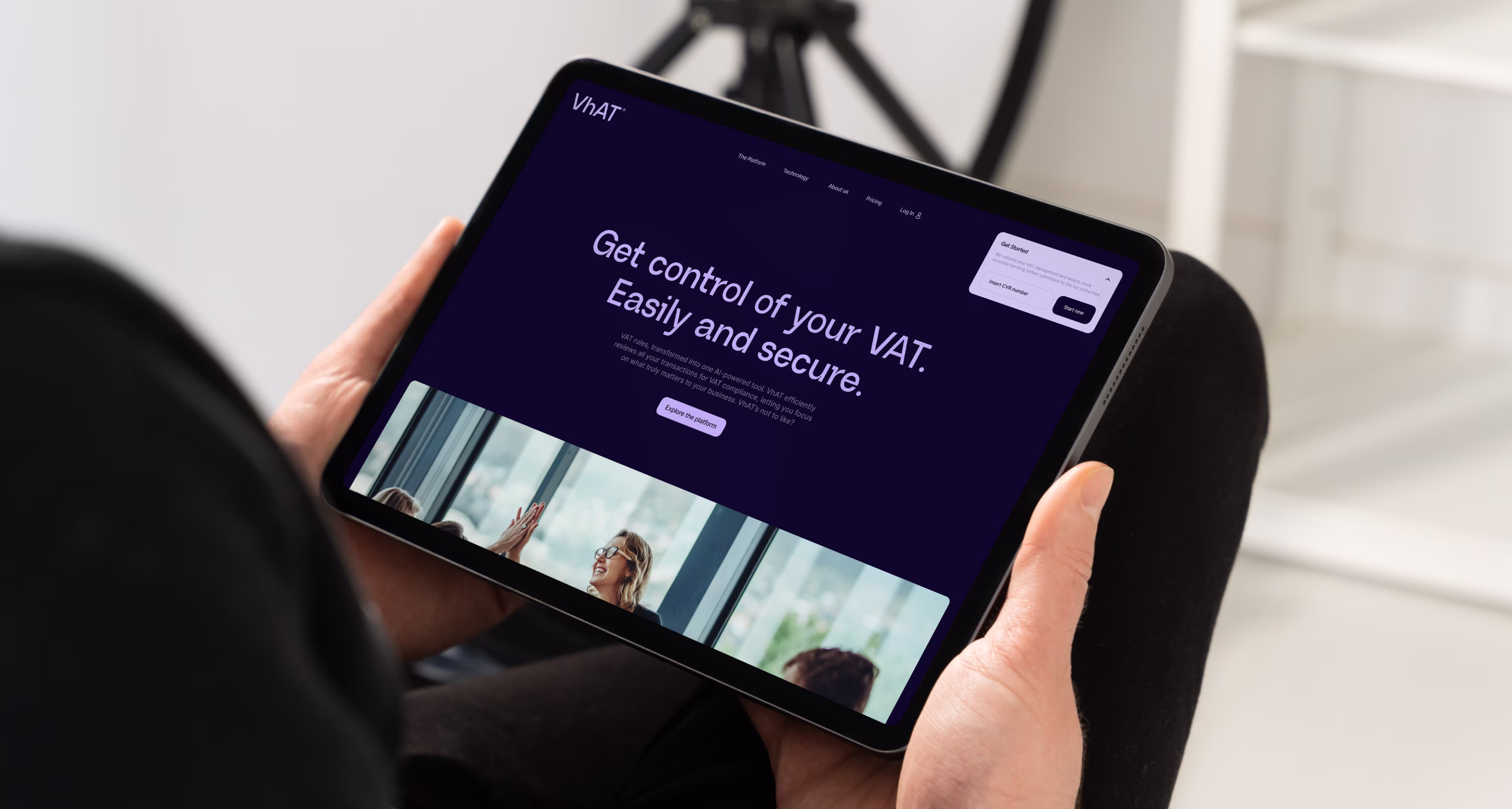 Person der holder tablet med hjemmeside med titlen "Get control of your VAT. Easily and secure." og call-to-action knap "Explore the platform".