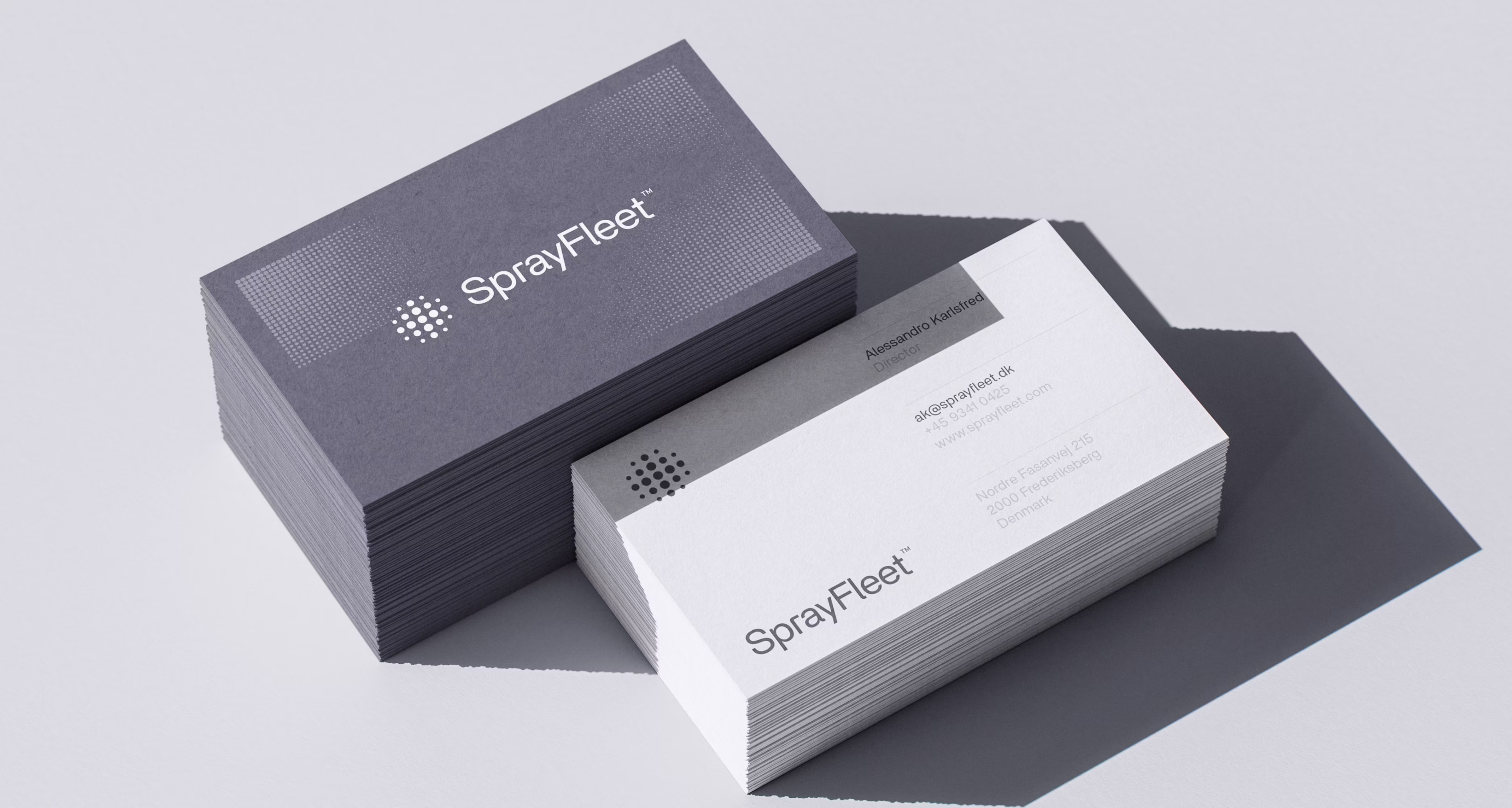 To stakke SprayFleet-visitkort, ét med mørkeblåt design og ét hvidt med kontaktoplysninger på Alessandro Karlsfred, Director.