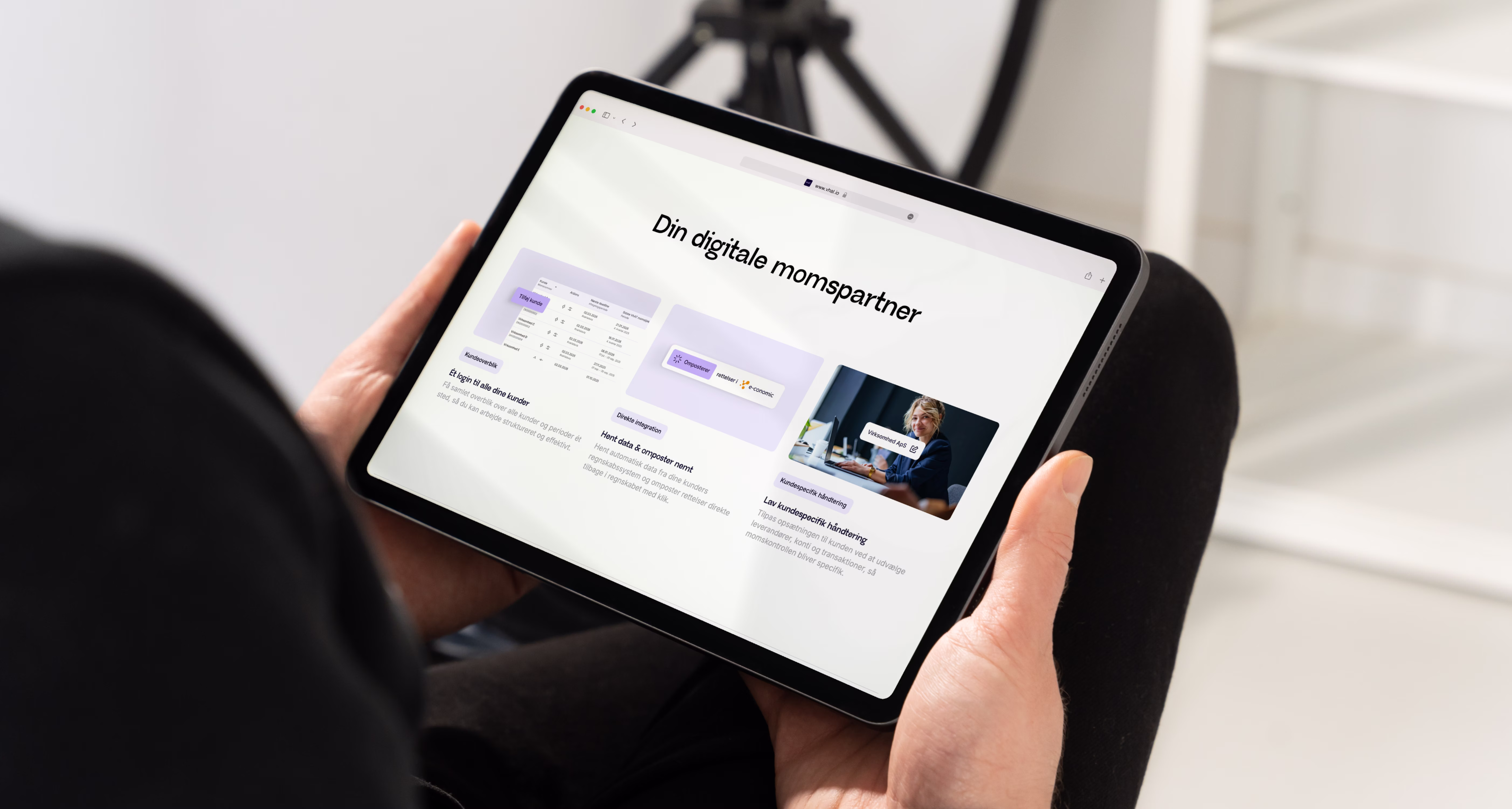 Billboard i metro med hånd der holder telefon med login-skærm til VhAT-app og tekst om din digitale partner til nem moms-gennemgang og fejlkorrigering.