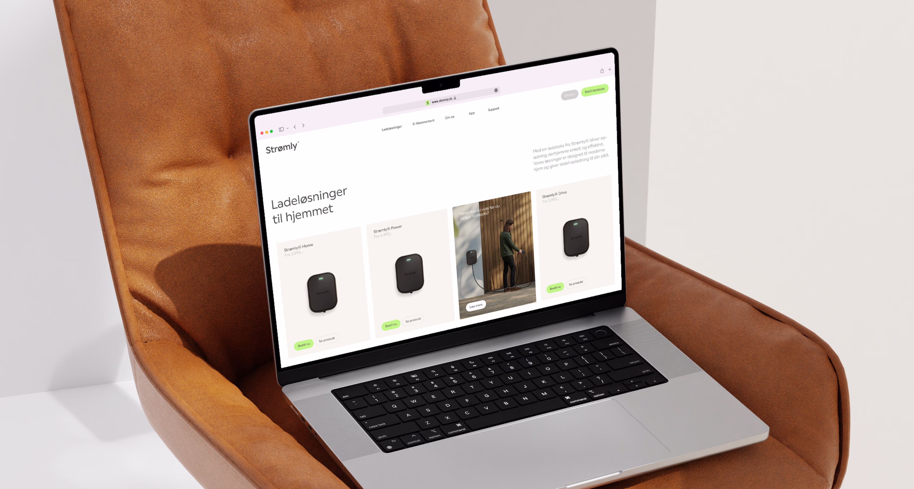 Hænder der holder en tablet med en hjemmeside, hvor en sort Strømly-enhed er monteret på en træoverflade.