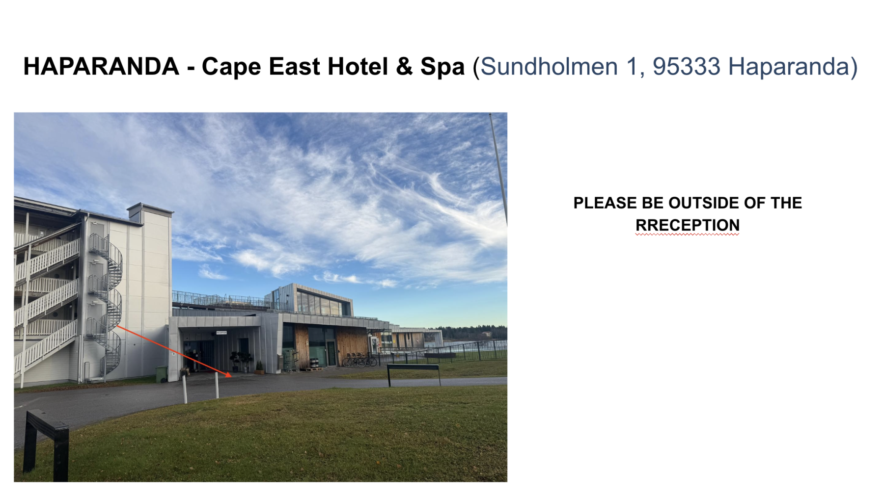 Exterior view of Cape East Hotel & Spa building with spiral staircase on the left and red arrow pointing to the reception entrance under a cloudy blue sky.