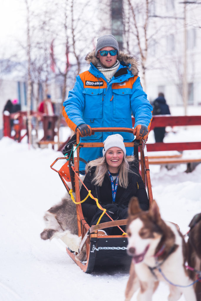 Torkil Hansen riding the dog sled with a happy tourist.