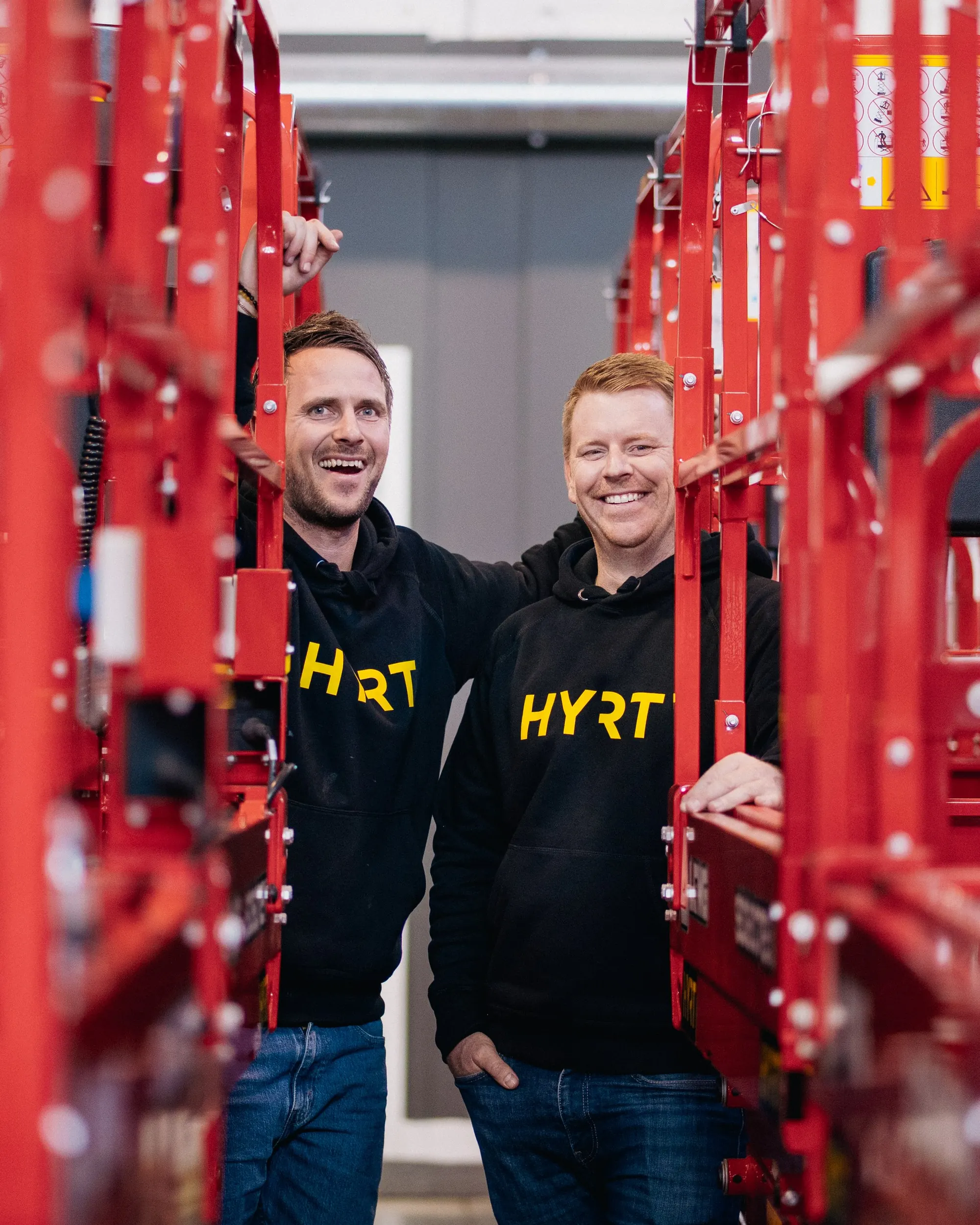 Kenneth og Petter smiler på plattformen til en sakselift i hallen