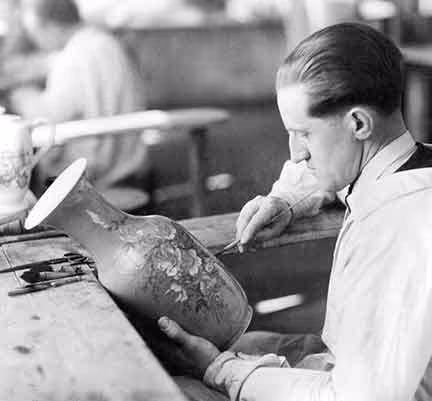 Photo historique Pillivuyt. Un homme en chemise blanche restaure une grande urne décorée dans un atelier Pillivuyt.