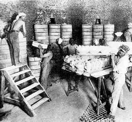 Photo historique Pillivuyt. Ouvriers dans la manufacture Pillivuyt remplissant et empilant des fûts métalliques.