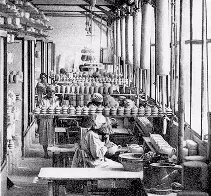 Photo historique de la manufacture de porcelaine Pillivuyt. Atelier de fabrication de porcelaine française avec plusieurs femmes travaillant à la fabrication et à la décoration des vases.