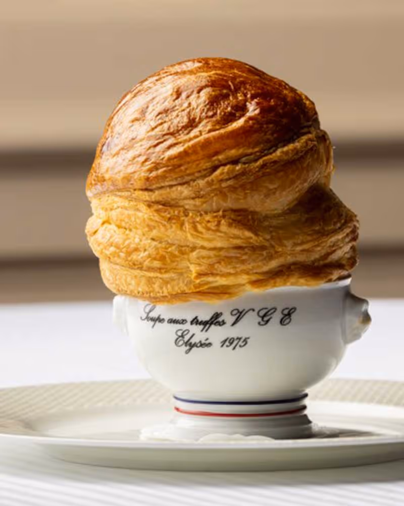 Soupe aux truffes en croûte dorée servie dans une petite soupière en porcelaine blanche Pillivuyt marquée VGE Élysée 1975.