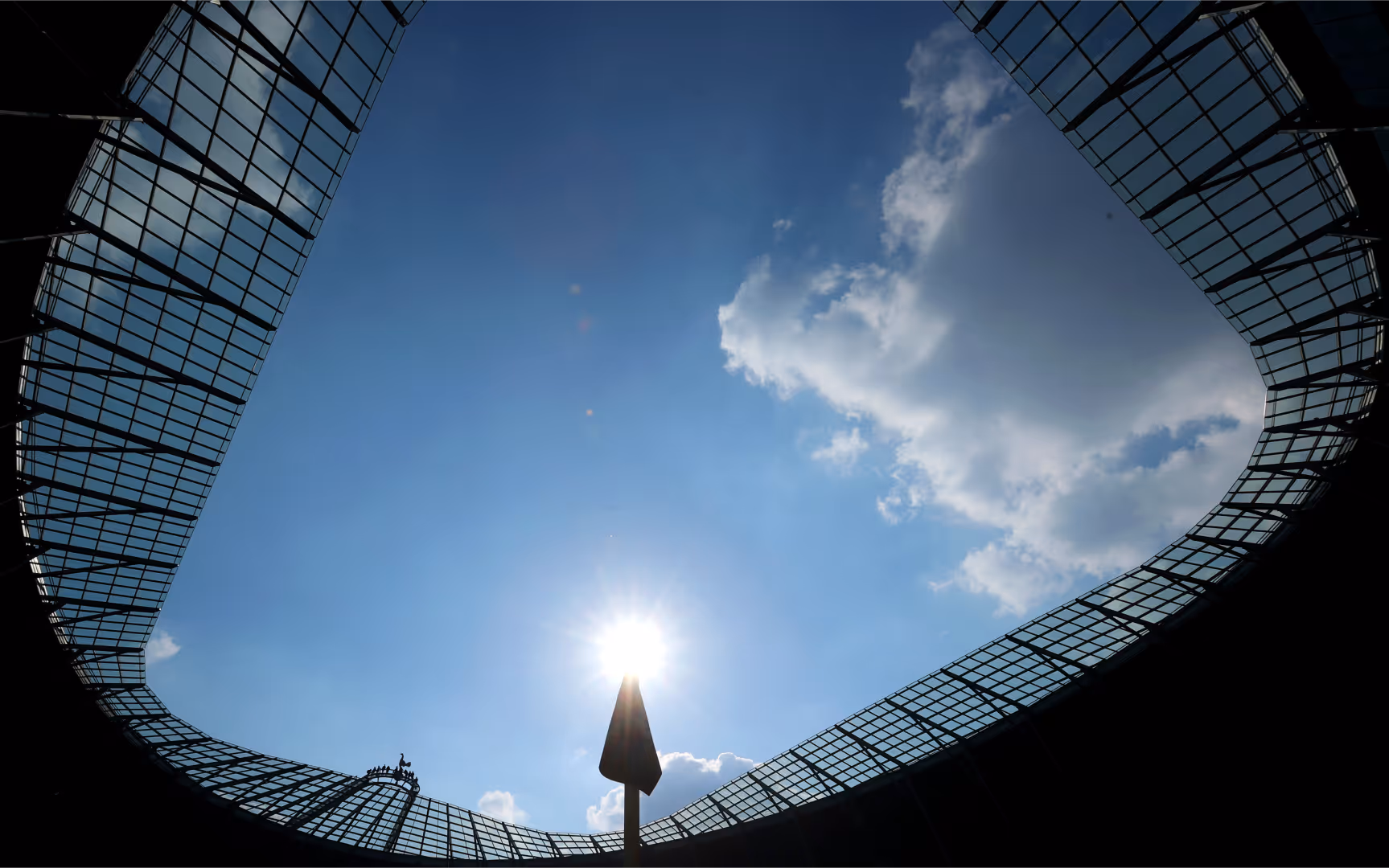 The Tottenham Hotspur Stadium is backlit by the sun.